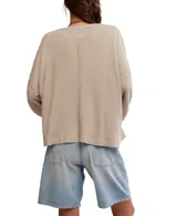 Buzo de punto waffle color beige, de algodón suave, con silueta relajada, hombros caídos, mangas largas, bolsillo frontal y escote amplio tipo barco.