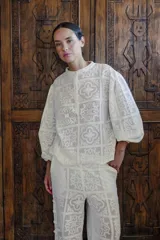 Blusa blanca con diseño calado, cuello mao y mangas 3/4 abullonadas.