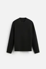 Jersey negro de punto con textura, corte relaxed fit, cuello redondo y manga larga.