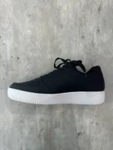 Zapatillas urbanas negras con suela blanca.