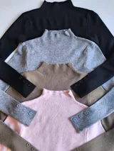 Polera fucsia de tejido de punto con cuello alto y mangas largas con botones decorativos en los puños.