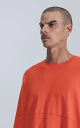 Remera de manga larga color naranja con cuello redondo.