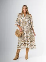 Vestido midi de algodón italiano, color blanco con estampado boho chic en tonos naranja, marrón y verde. Tiene corte oversized, mangas 3/4 con volados y cinturón de soga trenzada con hebilla circular.