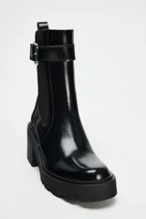 Botín negro estilo Chelsea con elástico lateral, hebilla decorativa y suela track con tacón bloque.
