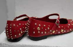 Chatas negras de cuero con correa sobre el empeine y hebilla plateada. Decoradas con tachas plateadas y doradas de diferentes tamaños.