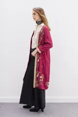 Saco largo de viscosa color fucsia con bordados dorados. Presenta un diseño con guarda bordada en el delantero, escote y puños, cuello redondo y cierre frontal con ganchos invisibles.