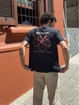 Camiseta negra con estampado en la espalda de una flor de hibisco color salmón y el logo de la marca Brixton.