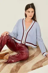 Cardigan celeste de punto trenzado, con escote en V y botones metálicos. Presenta ribetes a contraste en cuello, puños y bajo.