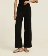 Pantalón wide leg negro de crepé, con cintura alta, pliegues, botón y trabillas.