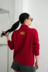 Campera tejida con textura vanizada a rayas horizontales en blanco y negro, con cierre frontal y flecos negros en forma de V en el pecho.