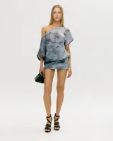 Vestido corto de lycra premium, color azul grisáceo con estampado abstracto en tonos óxido. Diseño asimétrico con un hombro descubierto y manga corta ancha.