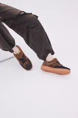 Zapatillas bajas de cuero sintético con estampado animal print, puntera y cordones negros, suela color caramelo y detalle en el talón color blanco.