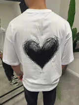 Remera blanca de algodón con estampado de un corazón negro en la espalda.