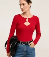 Blusa roja de viscosa con textura acanalada, cuello redondo, mangas largas y aberturas circulares en el busto con detalles metalizados.