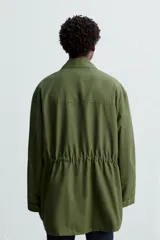 Parka verde militar de corte relaxed fit confeccionada en tejido técnico ligero. Cuello solapa y manga larga. Bolsillos de plastrón con solapa en delantero. Cintura ajustable en interior. Cierre frontal con cremallera oculta por solapa con botones a presión.