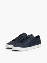 Zapatillas de corte bajo Tommy Hilfiger confeccionadas en una mezcla de piel color azul marino. Presentan un diseño atemporal con cordones al tono, suela de goma vulcanizada blanca y detalles distintivos de la marca, incluyendo el logo en el lateral, la lengüeta y el talón bordado.