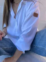 Camisa blanca de mangas largas con puños abotonados y cuello clásico.