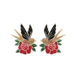 Pins decorativos en forma de golondrinas sobre flores rojas, ideales para accesorios diversos.