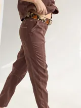 Pantalón largo color marrón, de lino, corte cigarette y tiro alto. Presenta costuras a contratono y bolsillos laterales. Se ajusta a la cintura con cinturón de cuero con estampado animal print. Diseño Margara hecho en Uruguay.