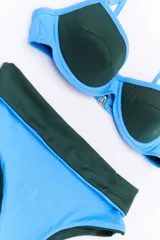 Conjunto de bikini negro y dorado, con corpiño triangular y bombacha clásica con cintura alta.