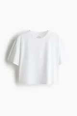 Remera deportiva blanca de corte boxy, confeccionada en tejido funcional DryMove™ que ayuda a absorber el sudor. Tiene cuello redondo, mangas cortas con hombros caídos y bajo recto.
