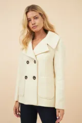 Chaquetón color crema con doble solapa, abrochadura doble, bolsillos delanteros y forro al tono.
