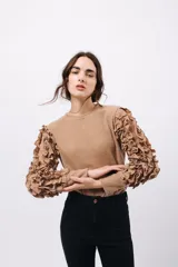 Remera negra de punto con mangas largas abullonadas con volantes.