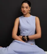 Vestido sin mangas, largo midi, color celeste claro, con escote redondo y corte evasé. Presenta breteles anchos y cierre trasero con cremallera.