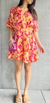 Vestido corto de color naranja con estampado floral en tonos fucsia y amarillo, con mangas abullonadas.