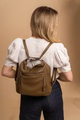 Cartera mochila color marrón de símil cuero suave con múltiples bolsillos con cierre, división al medio y correa ajustable de doble manija para llevar al hombro y como mochila.