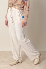 Pantalón ancho color beige de lino y rayón, con cintura elastizada ajustable con cordón y bolsillos laterales.