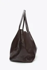 Bolso maxi shopper de cuero color marrón oscuro, con pespuntes a tono y asas de hombro. Incluye cierre con tiras y botón, y cartera con bolsillo extraíble.