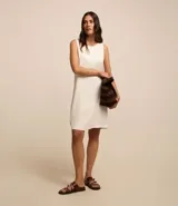 Vestido corto color crudo, confeccionado en viscolino, con escote redondo, breteles anchos y cierre en la espalda.