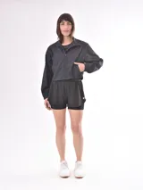 Campera corta deportiva color negro, con cuello alto, cierre frontal y mangas largas.