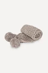 Bufanda tejida a mano en punto arroz color beige, con pompones en los extremos.