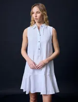 Vestido corto blanco de gasa, sin mangas, con cuello camisero, abertura central con botones y terminación de ruedo con volado.
