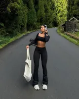 Conjunto negro compuesto por top corto de mangas largas y pantalón acampanado de tiro alto.