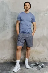 Remera deportiva azul de manga corta con cuello redondo, sección de malla en laterales y espalda, diseño reflectante en el pecho y atrás, y bajo recto. Corte musculoso con silueta entallada que realza el torso.