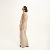 Vestido largo color beige, sin mangas, con cuello redondo y abertura lateral en el ruedo.