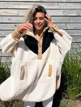 Buzo tipo poncho de polar color crudo con bloque superior en negro y detalles en beige.