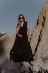 Mono largo color marrón chocolate, con escote en V, sin mangas, con hombreras y bolsillos laterales. Incluye accesorio tipo flor para usar como cinturón o collar.