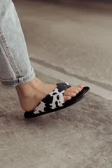 Sandalias tipo ojotas con base acolchada y estampado animal print de vaca en marrón y blanco.