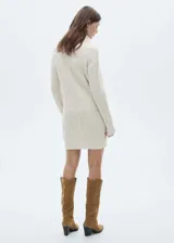 Vestido corto color crema de tejido de punto grueso con diseño trenzado, cuello alto y mangas largas.