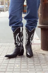 Botas texanas negras de cuero con bordados blancos y taco bajo.