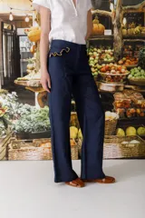 Pantalón de jean azul oscuro, de corte acampanado, con bolsillos delanteros con detalle de volados.