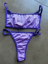 Conjunto de bikini de lycra color lila, con corpiño de corte recto con breteles regulables y bombacha tipo tanga con tiras regulables en los laterales.