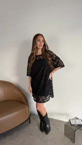 Vestido corto tipo remerón de encaje negro con mangas cortas.