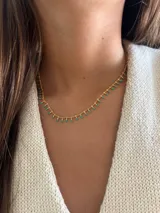 Collar dorado con cadena fina y pequeñas cuentas colgantes.