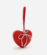 Billetera mediana roja con forma de corazón, cierre de cremallera, correa de mano y moño de perlas artificiales. Marca Satinato, colección Primavera/Verano 2025.