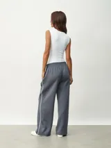 Pantalón deportivo color borgoña, de corte ancho y cintura elástica. Presenta una franja blanca vertical a lo largo de la pierna.